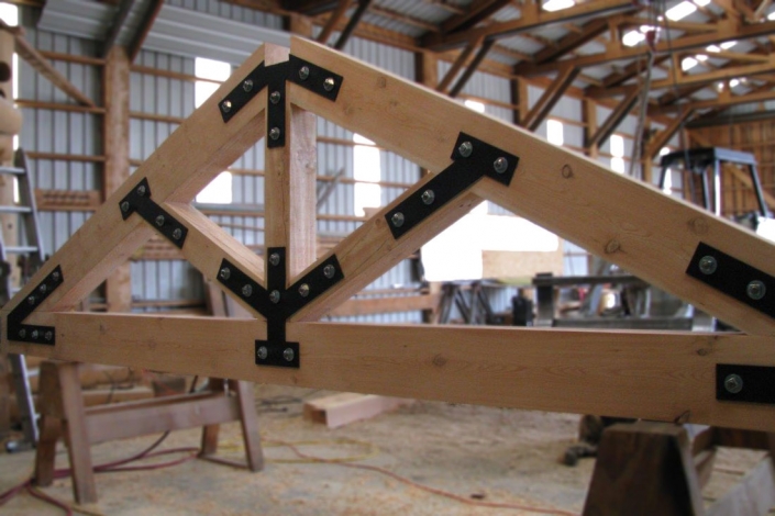 timber truss with exposed connectors on saw horses in shop